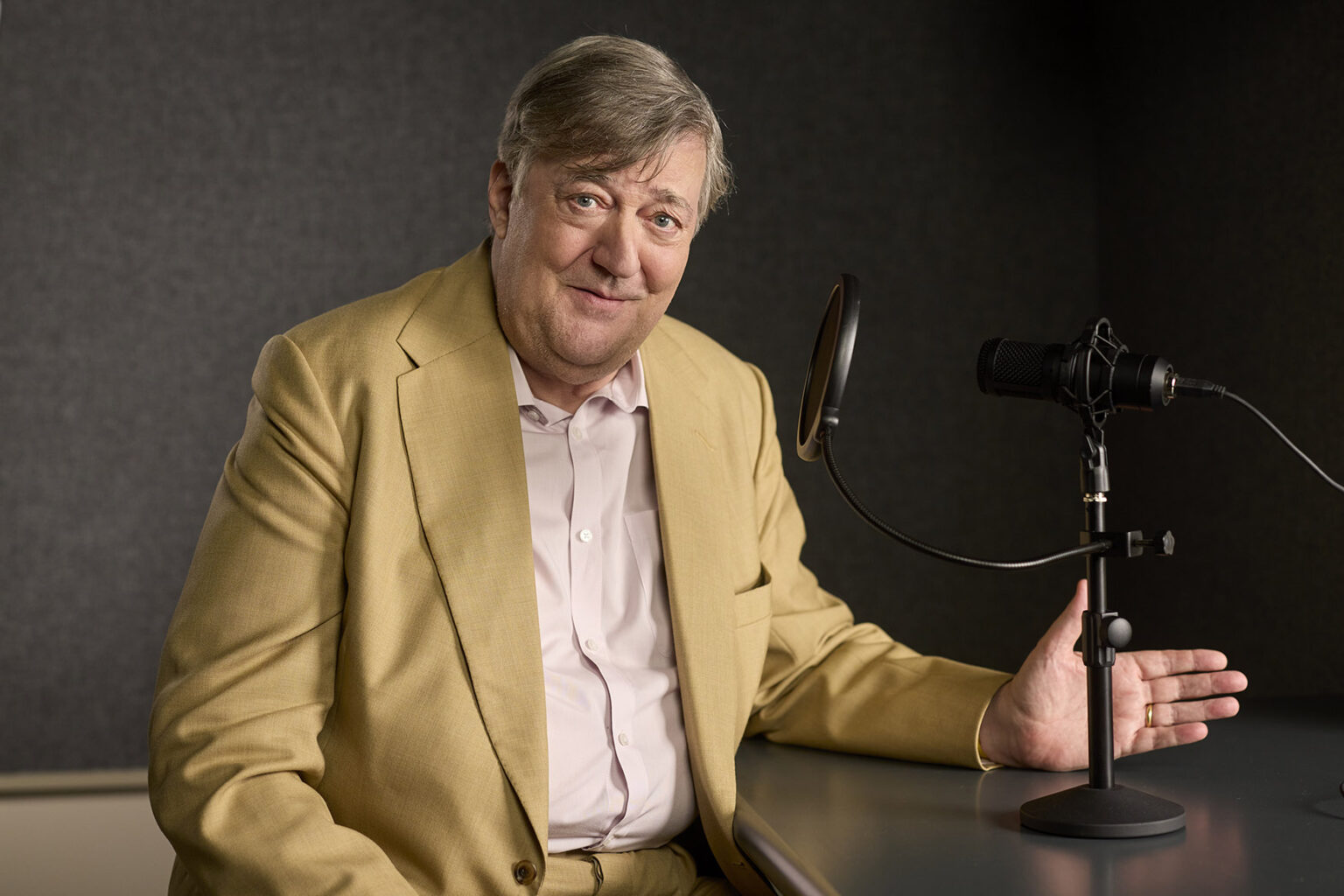 Sir Stephen Fry features at this year's Hay Festival 2025 installation, Vocalize. He features in front of a microphone.
